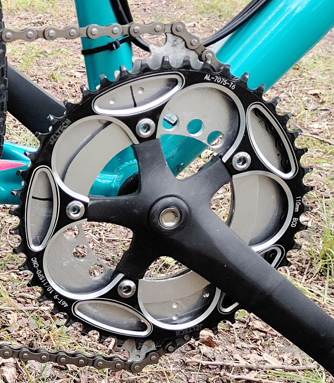 Closeup of the blue bike crank showing a standard chainring mounted beside a Crownring.